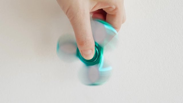 Girl playing with a glossy light colourful hand fidget spinner toy