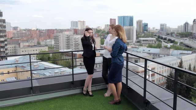 Beautiful Girls Communicate in Break at Work. Three Business Women Discuss Working on the Roof Overlooking the City