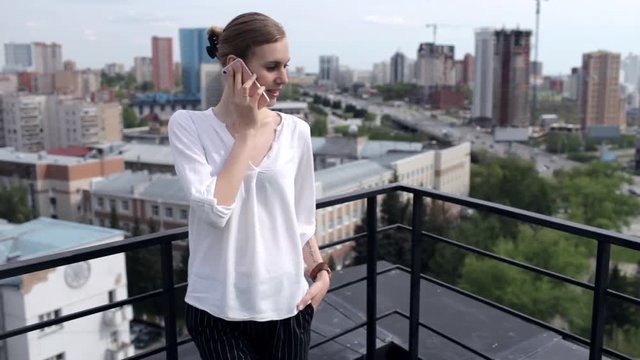 Beautiful Business Woman Talking on The Phone Standing on the Roof Overlooking the City