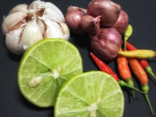 Closeup sliced lime,garlic head,shallot head and fresh chili,on black background,abstract design.