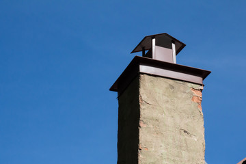 Cement chimney with cap against blue sky