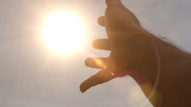 The hand holds up the sky catching the sun.
