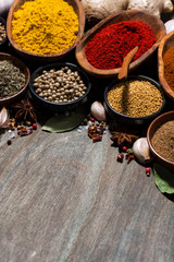 assortment of various spices on a wooden background, vertical top view