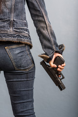 Woman in jeans is holding a gun in her hand.