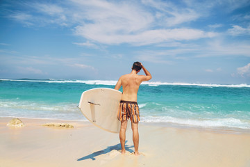 Fototapeta na wymiar Young surfer guy with surfboard enjoying on the beach.