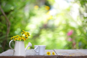 Fototapeta premium Yellow flower in white pot and coffee cup on wooden table