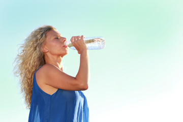 Frau mittleren Alters trinkt Mineralwasser im Sommer bei Hitze