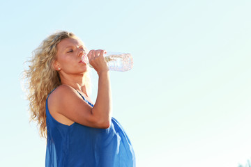 Frau mittleren Alters trinkt Mineralwasser im Sommer bei Hitze