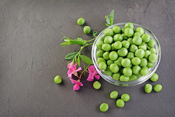 .Healthy food. Fresh green peas in glass bowl with pink flowers of sweet pea