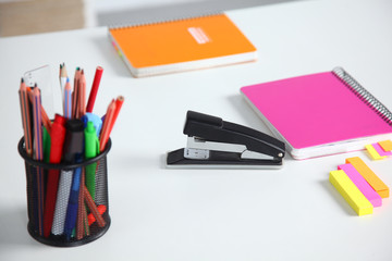 Fototapeta premium Closeup of white desktop with notepads, pen, coffee cup and other items. Selective focus.