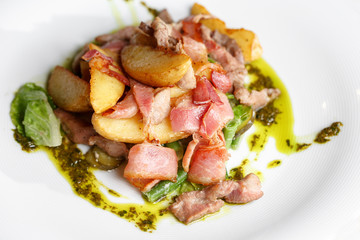 Fried potato with bacon and green beans on plate over wooden background.