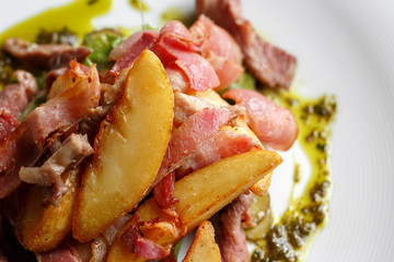 Fried potato with bacon and green beans on plate over wooden background.