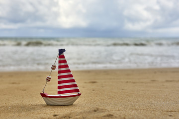 Small toy sailing yacht on the beach