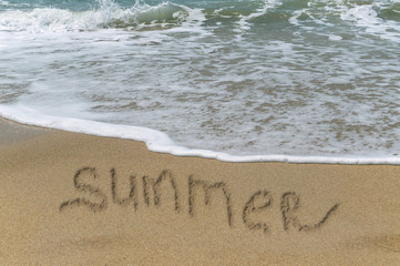 sea waves with summer sign on sand
