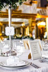 Frame with lettering on white paper inside stands on the dinner table number three