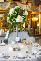 Tall bouquet of blue and white hydrangeas stands in the middle of dinner table number three