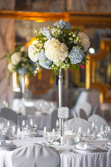 Table number five decorated with white hydrangeas stands in the rich hall
