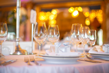 Wineglasses stand side by side on white dinner table