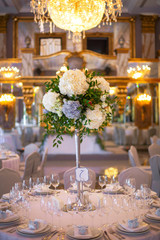 Table number seven decorated with white hydrangeas stands in the rich hall