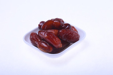 Delicious dried organic dates on bowl isolated over white background.