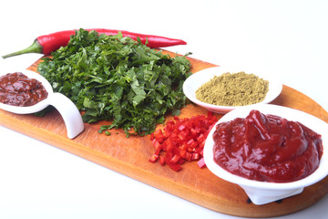 Fresh green cilantro, coriander leaves, tomato paste, chili pepper and spices on a wooden board. Ingredients for meat sauce.