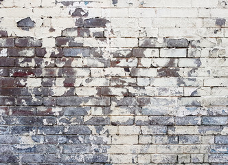 White paint peeling off old brick wall