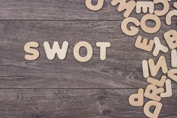 Word made with wooden letters next to a pile of other letters over the wooden board