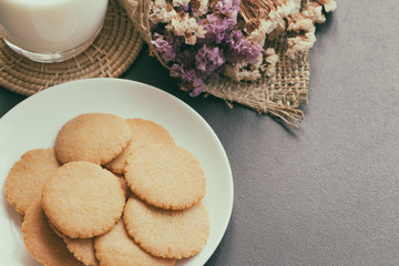 Homemade bakery:Thin biscuits or cookies baked from multi grains so delicious, crisp and crack snack. Biscuits cookies on granite table serve with fresh milk. Golden brown cookies on white plate.