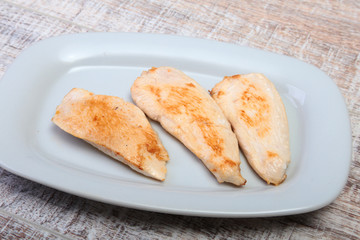Slices of roasted chicken breast and tomato on white plate