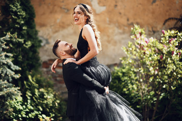 Man holds his smiling woman in black dress up