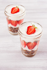 Healthy breakfast with strawberry and chocolate corn flakes in jar on white wood board.