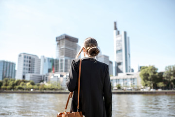 Businesswoman standing back on the quay with great view on the skyscrapers in Frankfurt city