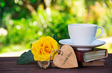A cup of summer tea on a stack of books and a fragrant yellow rose. Romantic concept. Copy space