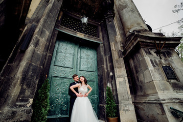 Bride and groom admire each other standing before green door