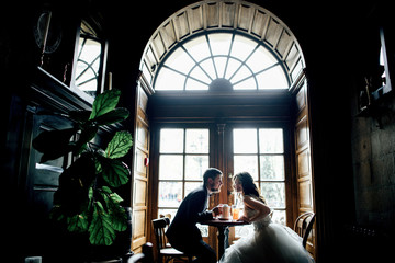 Lovely wedding couple sits at the little table in the cafe