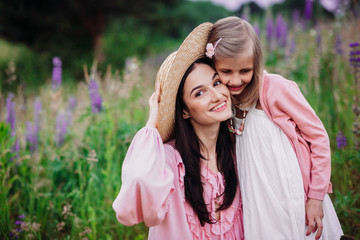 Woman and little girl in pink dresses pose on the field of lavander