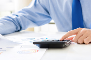 Fototapeta premium Businessman pressing calculator, calculating and analyzing financial data