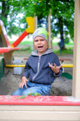 Unhappy Young boy playing in the sandbox