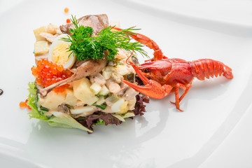 Olivier salad with trout in a white plate.