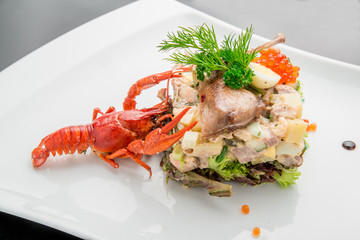Olivier salad with trout in a white plate.