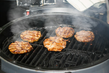Cooking meat for hamburgers on the barbecue grill in the street