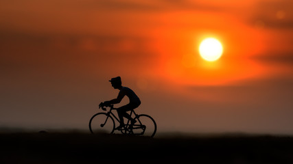 Fototapeta na wymiar Silhouettes model of cyclists on the beach with sunset.