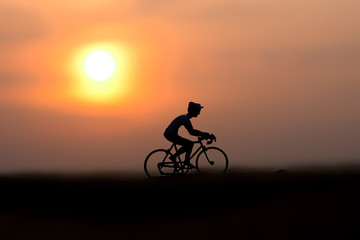 Naklejka na ściany i meble Silhouettes model of cyclists on the beach with sunset.