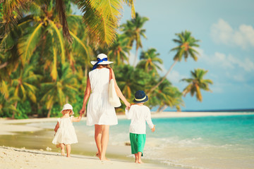 mother with little son and daughter walk on beach