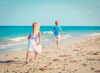 little boy and girl running on beach