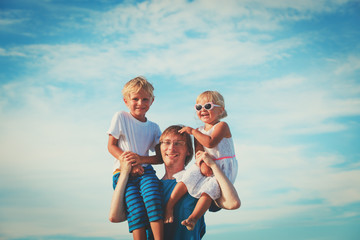 Fototapeta na wymiar happy father with two kids on shoulders at sky
