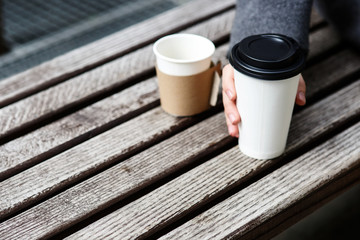 Man with grey sleeve takes paper cup of coffee