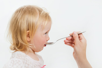 the little girl is spoon-fed