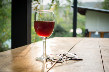 Wine glass and glasses on wooden table among sunset.