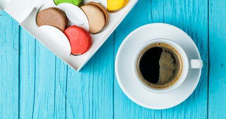 Macaroons with coffee on table